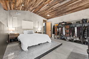 Bedroom with finished concrete floors, lofted ceiling, and recessed lighting