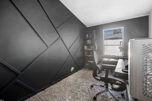 Office with a textured ceiling and light carpet