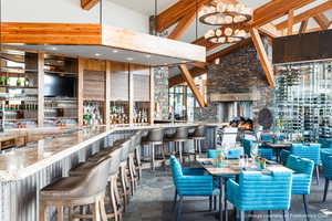 Dining area with stone tile flooring, a high ceiling, a community bar, and beamed ceiling