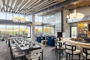 Dining area featuring a chandelier, a towering ceiling, a community bar, and dark carpet