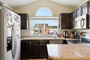 Kitchen with stainless steel appliances, dark wood finish cabinetry, and light countertops