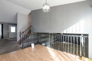 Stairway with wood finished floors, hanging lights, and carpet flooring