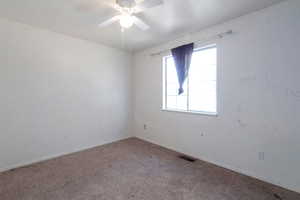 Carpeted empty room with ceiling fan and baseboards