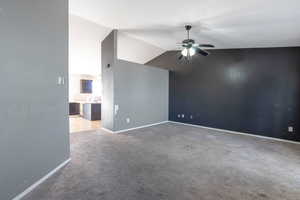 Spare room featuring a ceiling fan, lofted ceiling, and light colored carpet