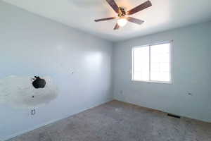 Carpeted empty room with a ceiling fan and baseboards