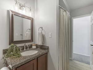Full bath featuring curtained shower, vanity, and wood tiled floors