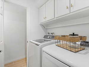 Laundry room featuring wood tiled floors, cabinet space, and washer and clothes dryer
