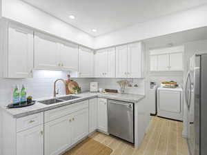 Kitchen featuring white cabinets, stainless steel appliances, light stone countertops, backsplash, and wood tiled floors