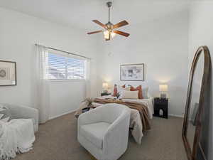 Carpeted bedroom featuring ceiling fan and a high ceiling