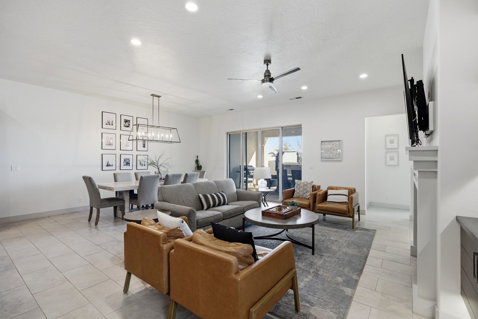 Living room featuring a ceiling fan, suspended lighting, and light tile patterned floors