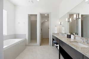 Full bathroom featuring a bath, double vanity, light tile patterned floors, and a tile shower