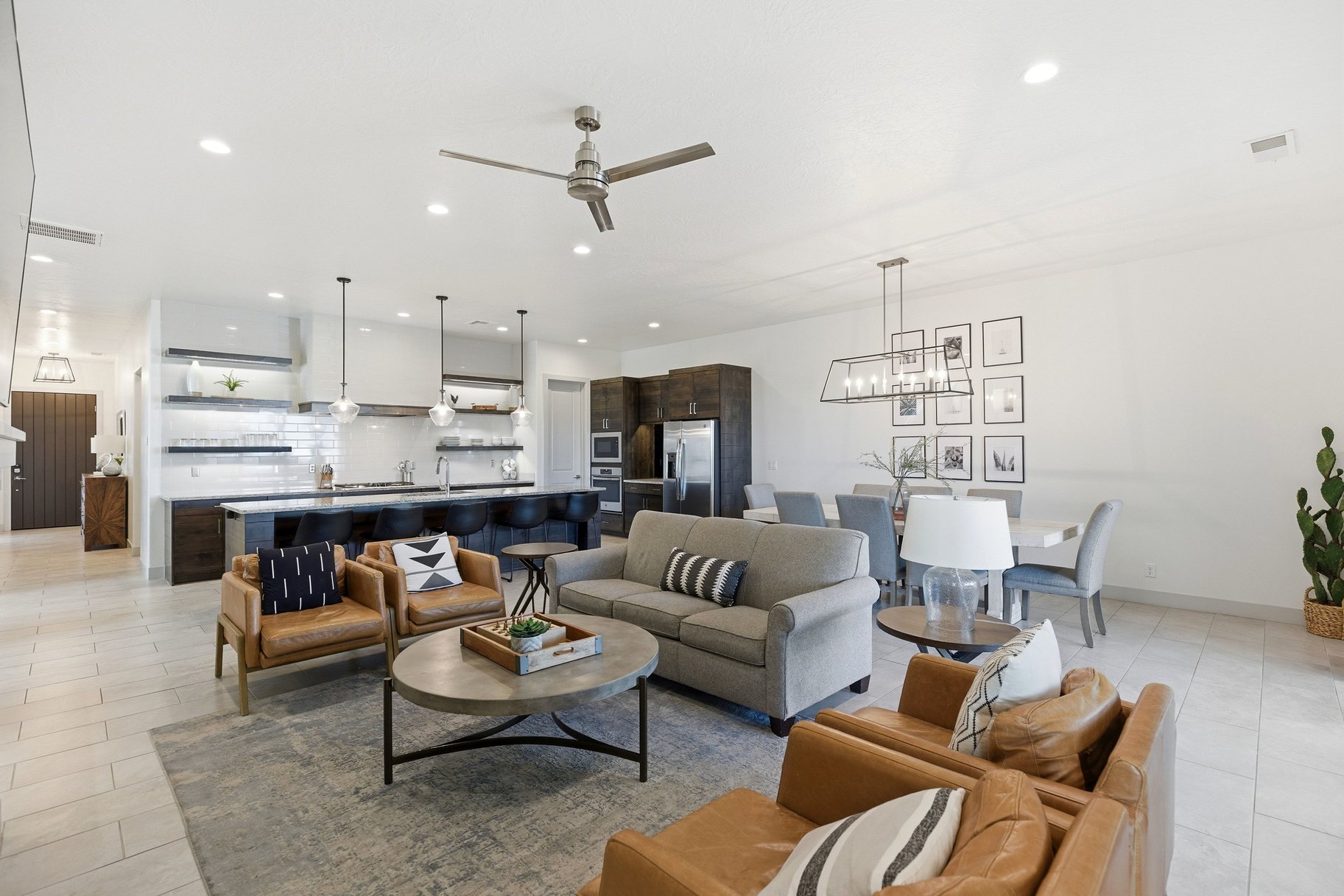 Living area featuring light tile patterned floors, ceiling fan, and a chandelier
