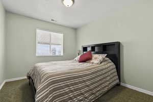 Bedroom with baseboards and dark colored carpet