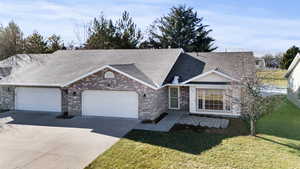 Ranch-style home featuring a shingled roof, a front lawn, driveway, and brick siding