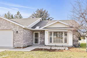 Ranch-style house featuring roof with shingles, a garage, and brick siding