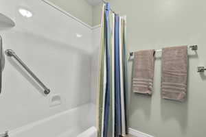 Full bath featuring shower / bath combo with shower curtain and baseboards