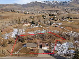 Snowy aerial view with property boundaries highlighted, a mountain view, and a residential view