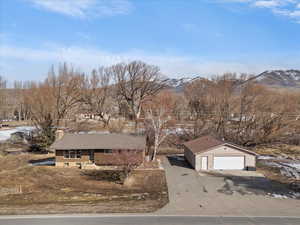 View of front of property featuring an outdoor structure, a chimney, a detached garage, a mountain view, and concrete driveway