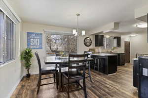 Dining room with hanging lights and dark wood-type flooring