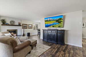 Living room with dark wood-style floors and a brick fireplace