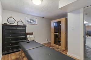 Bedroom with a sauna, light wood finished floors, and a textured ceiling