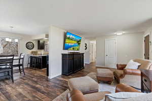 Living area with dark wood-style floors and a chandelier