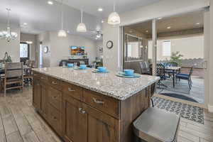 Kitchen with a kitchen island, light stone countertops, wood tiled floors, and ceiling fan
