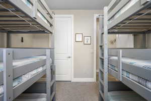 Bunk room with light carpet and baseboards