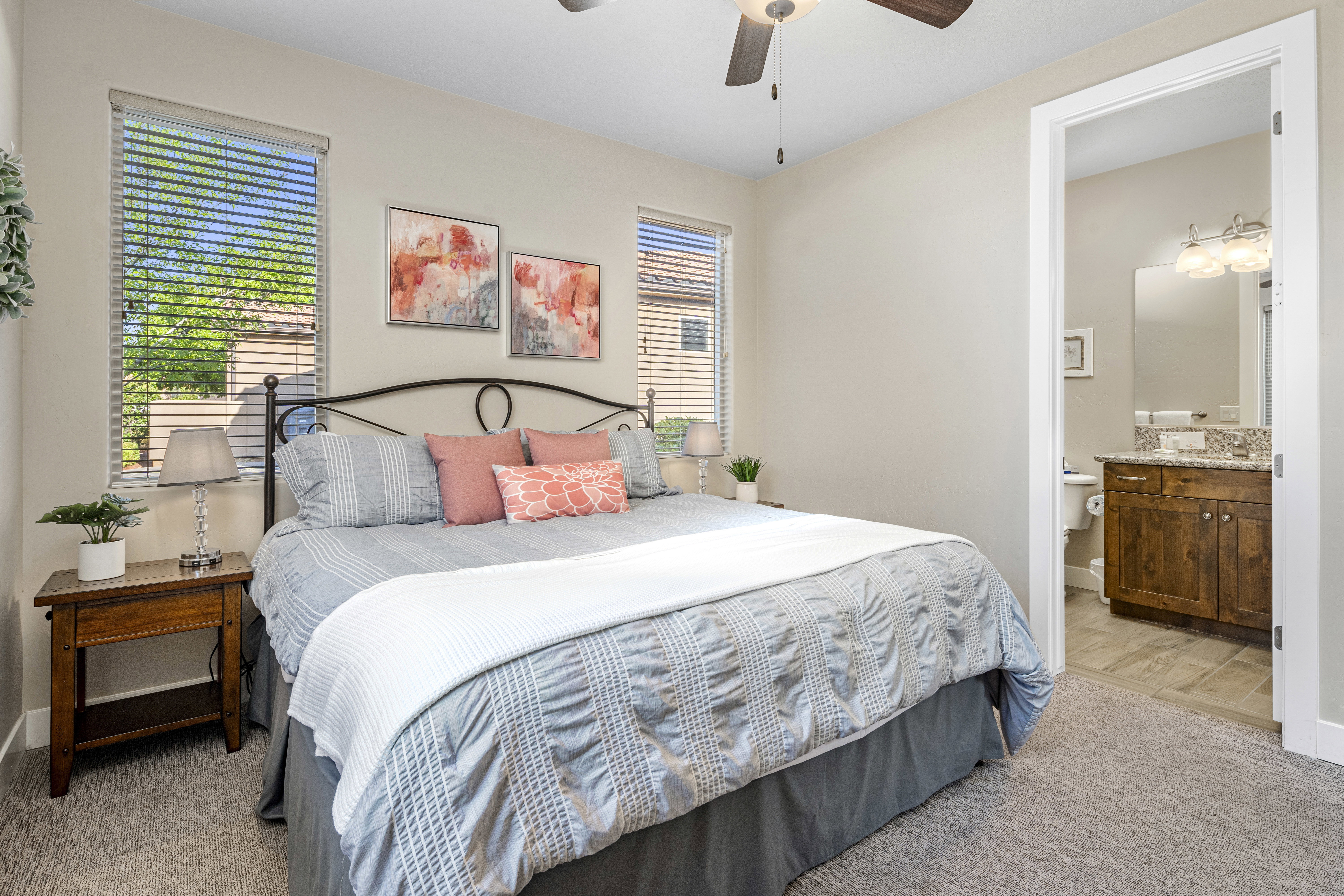Casita bedroom featuring light colored carpet, ceiling fan, and ensuite bath