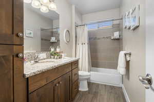 Bathroom with vanity, dark wood-style floors, and shower / bathtub combination with curtain