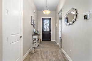 Entry Doorway to outside with baseboards and wood finished floors