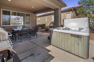 View of patio with outdoor dining area, a hot tub, and grilling area