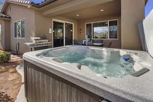 View of pool with patio surround, a hot tub, and grilling area