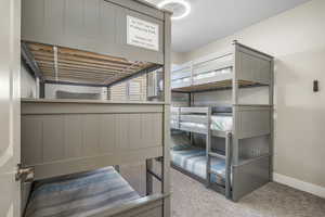 Bunk room featuring light carpet and baseboards