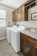 Laundry room with cabinet space, light wood-style flooring, and washing machine and dryer