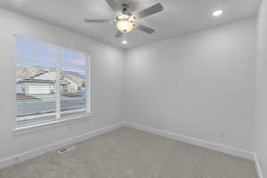 Carpeted spare room with a ceiling fan and recessed lighting