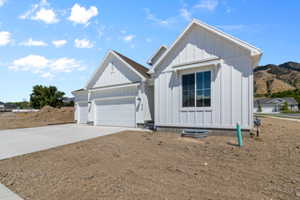 View of front of property featuring concrete driveway, an attached garage, and board and batten siding