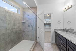 Bathroom featuring a stall shower, vanity, light tile patterned flooring, ceiling fan, and light colored carpet