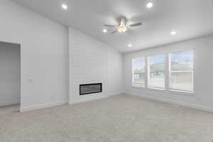 Unfurnished living room with lofted ceiling, a ceiling fan, light colored carpet, recessed lighting, and a fireplace