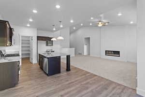 Kitchen featuring light stone countertops, dark wood finish cabinetry, pendant lighting, a kitchen breakfast bar, and vaulted ceiling