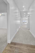 Corridor with light colored carpet, light wood-style floors, and recessed lighting
