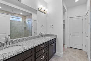 Full bathroom featuring double vanity, a shower stall, recessed lighting, light tile patterned flooring, and a walk in closet