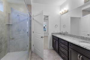 Bathroom featuring double vanity, a stall shower, and light tile patterned floors