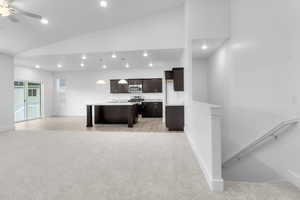 Unfurnished living room featuring light carpet, a ceiling fan, lofted ceiling, and recessed lighting