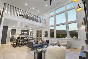 Living area featuring a mountain view, a high ceiling, light wood-style flooring, suspended lighting, and ceiling fan