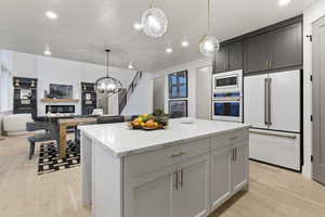Kitchen featuring high end white fridge, open floor plan, light stone countertops, a center island, and stainless steel oven