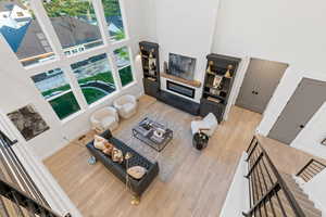 Living area with a high ceiling, light wood-style floors, and a glass covered fireplace