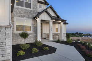 Property entrance with stone siding, board and batten siding, a standing seam roof, and a porch