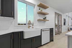 Kitchen featuring light stone counters, light wood finished floors, and white dishwasher