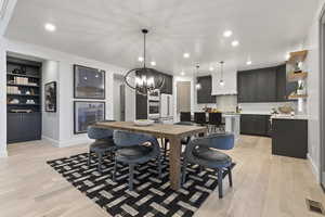 Dining area with light wood finished floors, built in features, and a chandelier